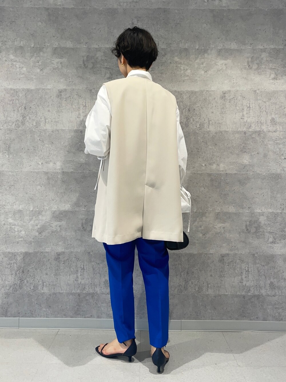 ブルー系のその他パンツ、ブラック系のボストンバッグ、ホワイト系のベストを着用したレディースの春コーディネートの3枚目の写真