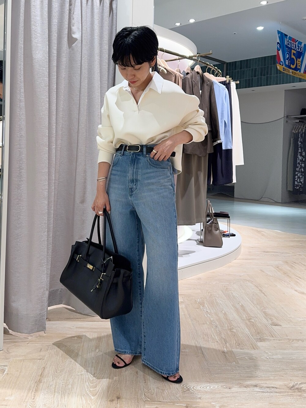 ブルー系のデニムパンツ、ブラック系のトートバッグ、ホワイト系のTシャツ/カットソーを着用したレディースの秋コーディネートの2枚目の写真