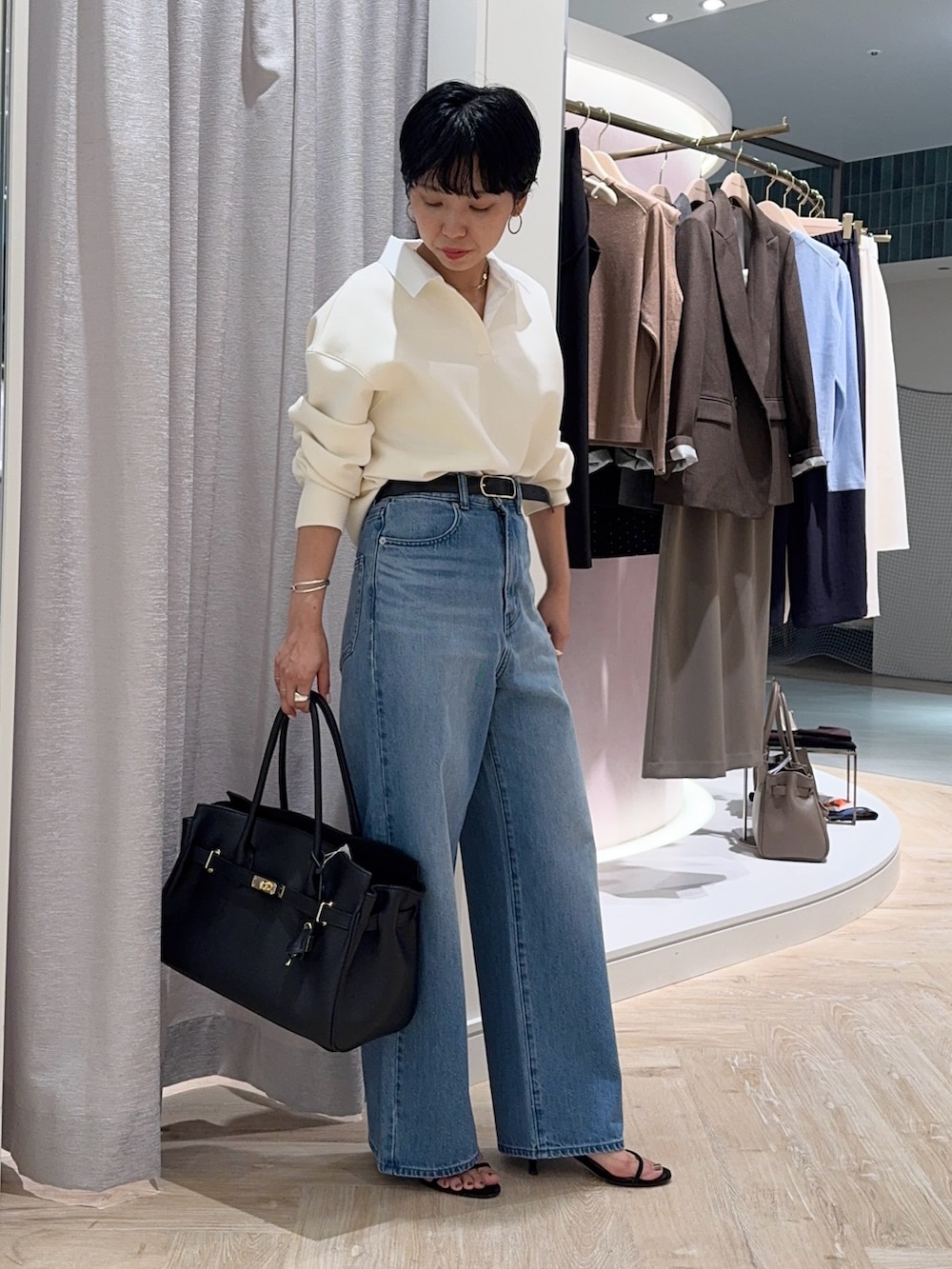 ブルー系のデニムパンツ、ブラック系のトートバッグ、ホワイト系のTシャツ/カットソーを着用したレディースの秋コーディネートの4枚目の写真