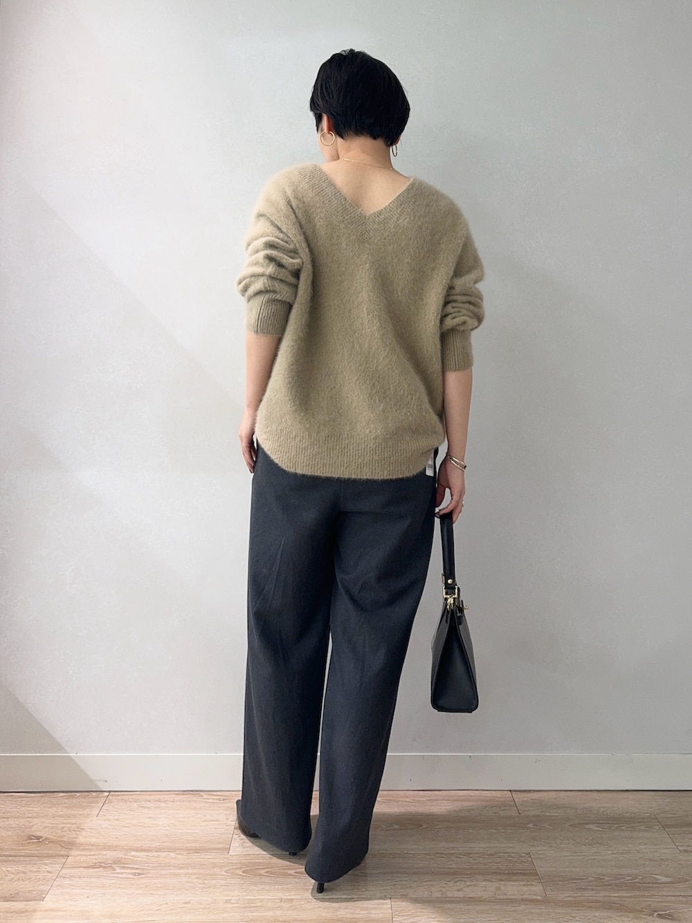 イエロー系のニット/セーター、グレー系のその他パンツ、ブラック系のショルダーバッグを着用したレディースの冬コーディネートの2枚目の写真