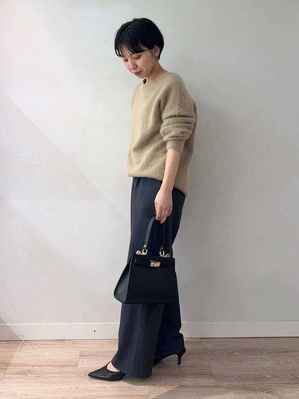 イエロー系のニット/セーター、グレー系のその他パンツ、ブラック系のショルダーバッグを着用したレディースの冬コーディネートの3枚目の写真