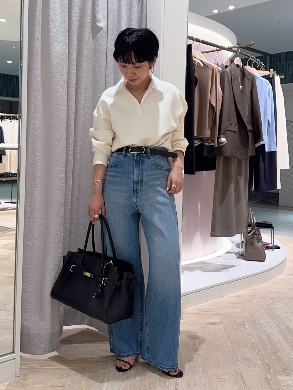 ブルー系のデニムパンツ、ブラック系のトートバッグ、ホワイト系のTシャツ/カットソーを着用したレディースの秋コーディネートの3枚目の写真