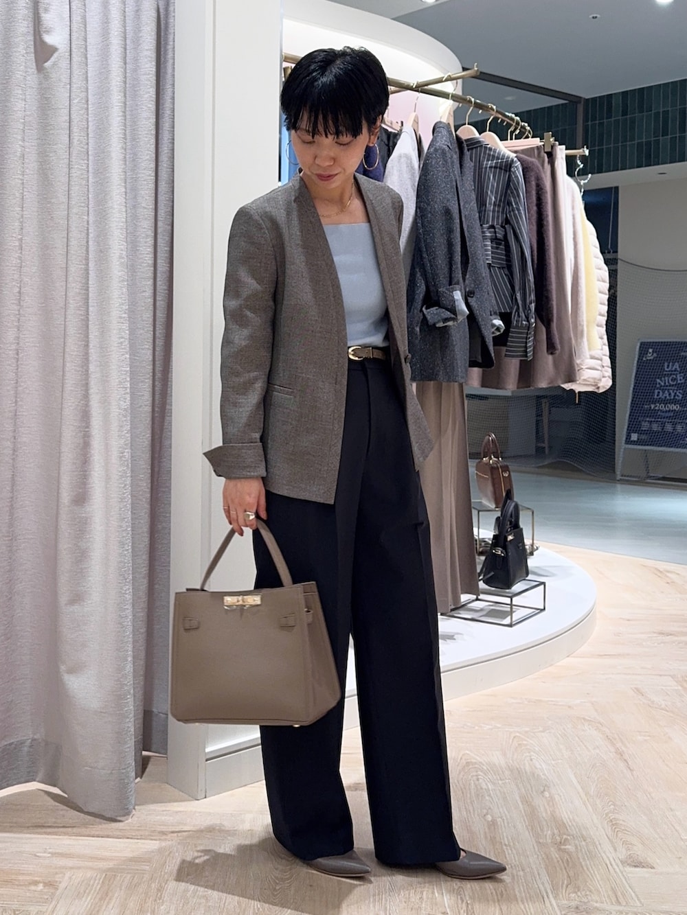 ブルー系のニット/セーター、ベージュ系のノーカラージャケット、ベージュ系のショルダーバッグを着用したレディースの秋コーディネートの3枚目の写真