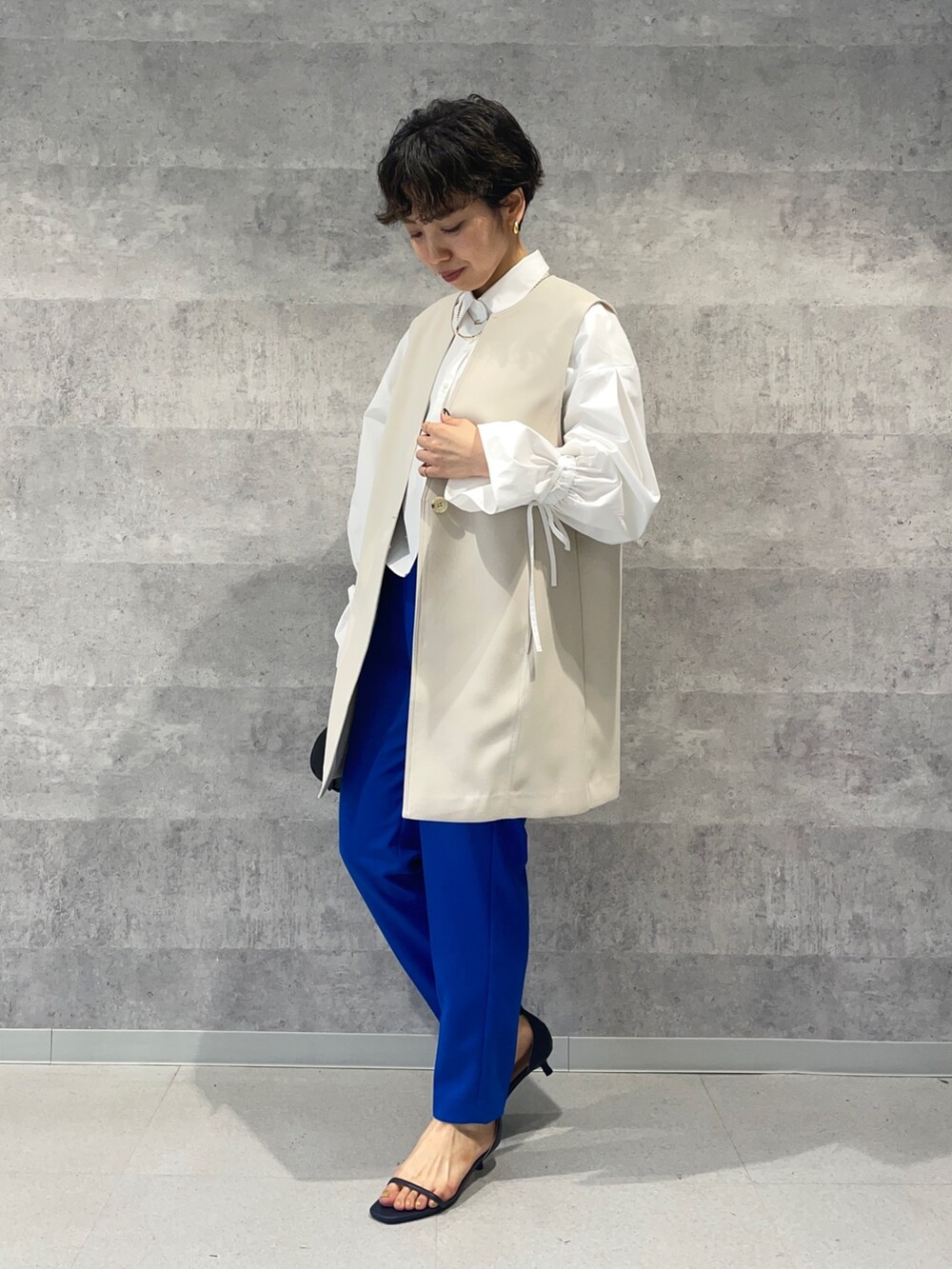 ブルー系のその他パンツ、ブラック系のボストンバッグ、ホワイト系のベストを着用したレディースの春コーディネートの2枚目の写真