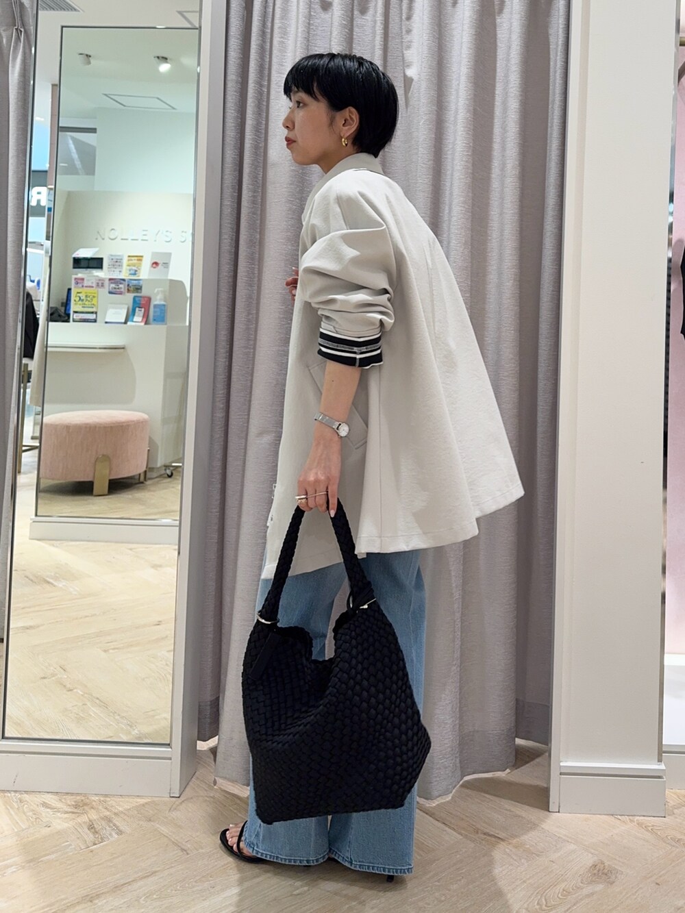 ブラック系のTシャツ/カットソー、ベージュ系のステンカラーコート、ブラック系のショルダーバッグを着用したレディースの春コーディネートの2枚目の写真