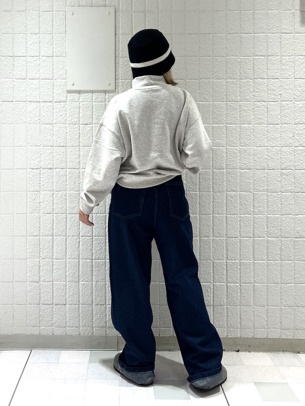 ベージュ系のスウェット、ブルー系のデニムパンツ、ブラック系のハットを着用したレディースの秋コーディネートの2枚目の写真