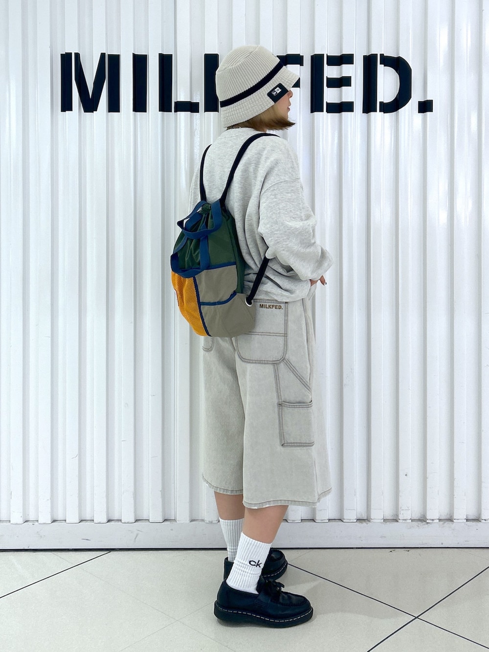 ホワイト系のデニムパンツ、ベージュ系のスウェット、グリーン系のバックパック/リュックを着用したレディースの秋コーディネートの2枚目の写真