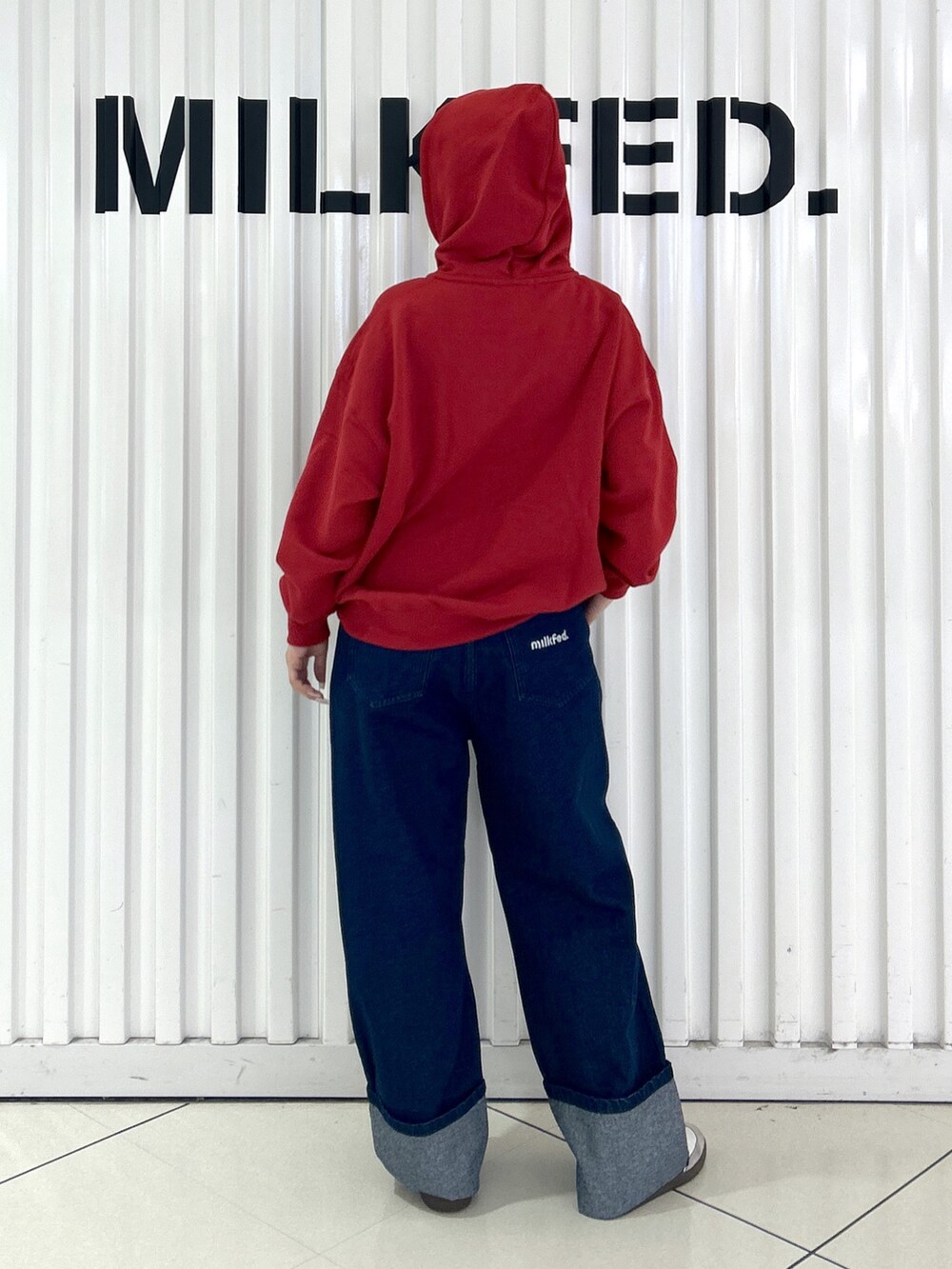 ブルー系のデニムパンツ、レッド系のパーカー、ブラック系のキャップを着用したレディースの秋コーディネートの2枚目の写真