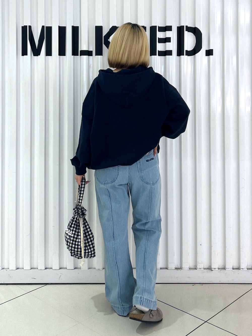 ブルー系のパーカー、ブルー系のデニムパンツ、ブラック系のお弁当箱を着用したレディースの秋コーディネートの2枚目の写真