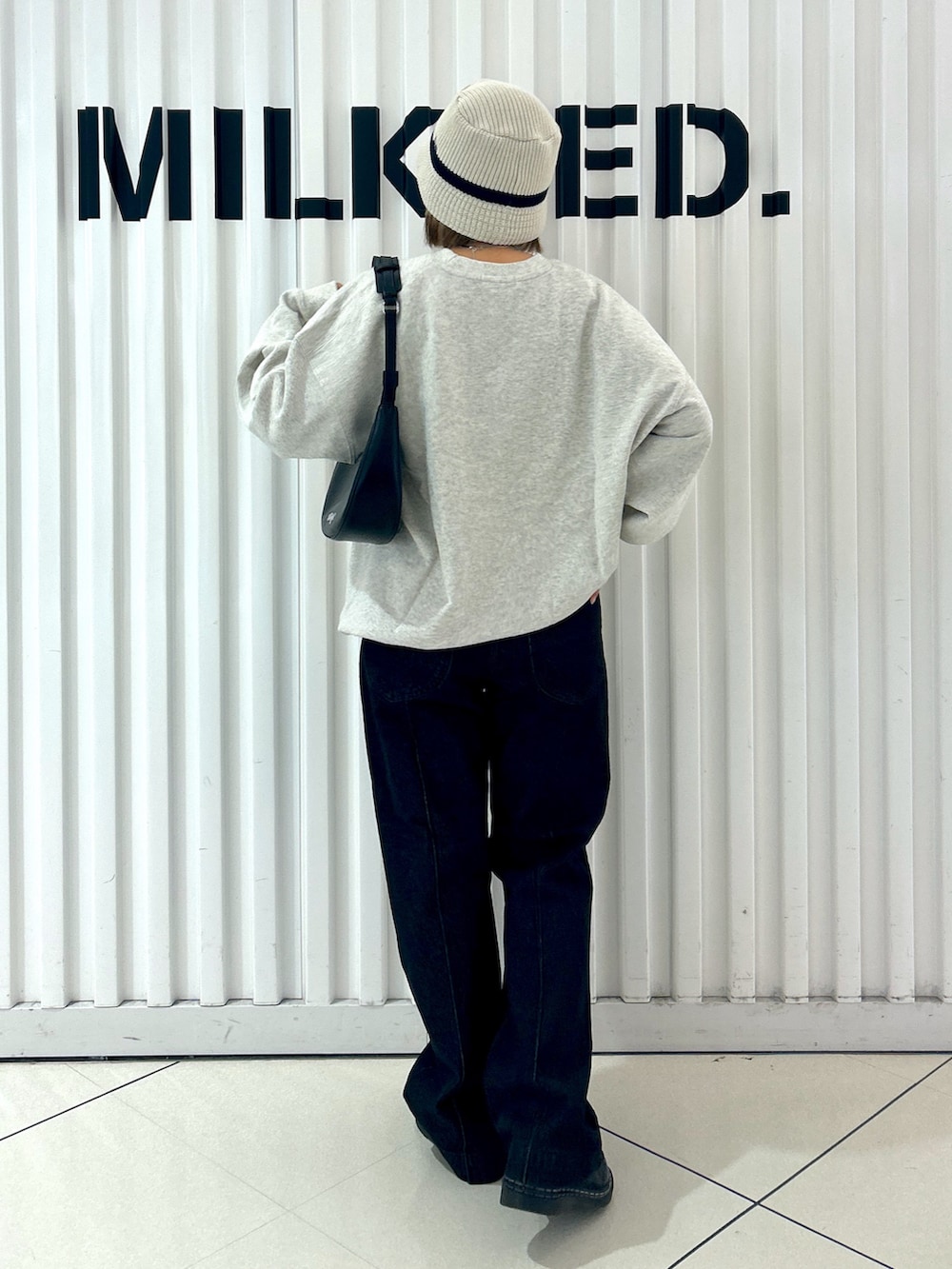 ベージュ系のスウェット、ブラック系のデニムパンツ、ブラック系のハンドバッグを着用したレディースの秋コーディネートの2枚目の写真