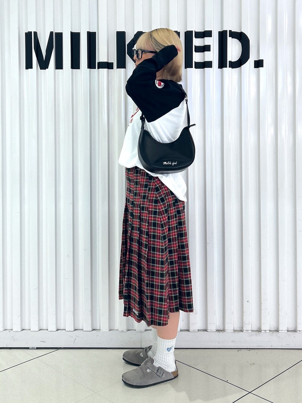 ブラック系のスカート、ホワイト系のTシャツ/カットソー、ブラック系のハンドバッグを着用したレディースの夏コーディネートの2枚目の写真