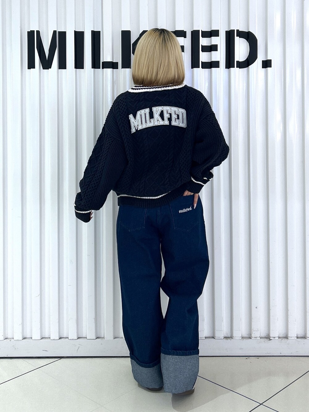 ブルー系のニット/セーター、シルバー系のショルダーバッグ、ブルー系のデニムパンツを着用したレディースの秋コーディネートの4枚目の写真