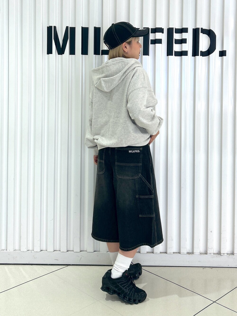 ブラック系のデニムパンツ、ベージュ系のパーカー、ブラック系のキャップを着用したレディースの秋コーディネートの2枚目の写真