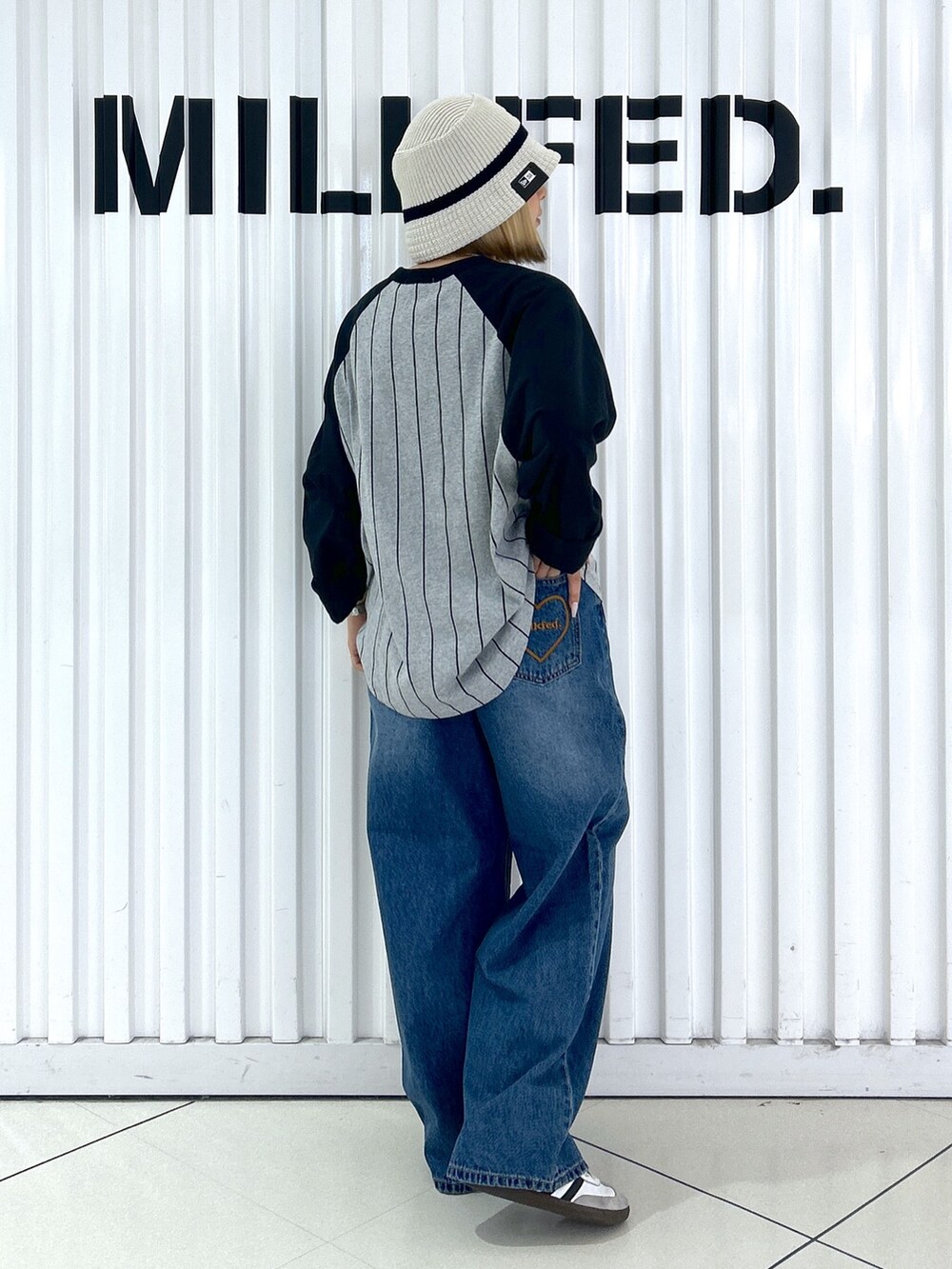 グレー系のTシャツ/カットソー、ブラック系のデニムパンツ、ホワイト系のハットを着用したレディースの秋コーディネートの2枚目の写真