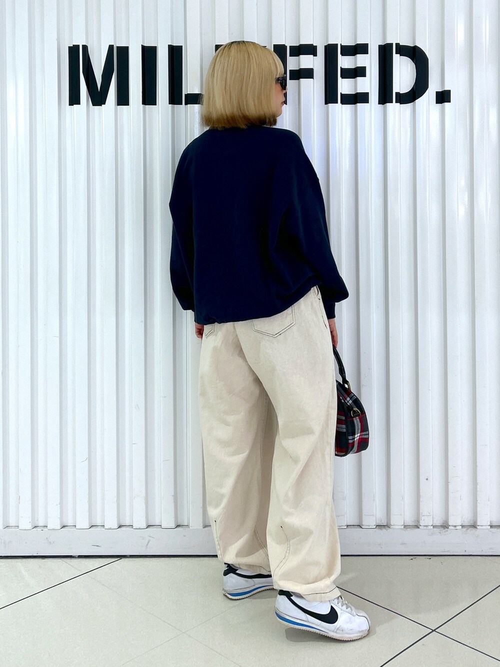グレー系のショルダーバッグ、ブルー系のスウェット、ホワイト系のデニムパンツを着用したレディースの夏コーディネートの3枚目の写真