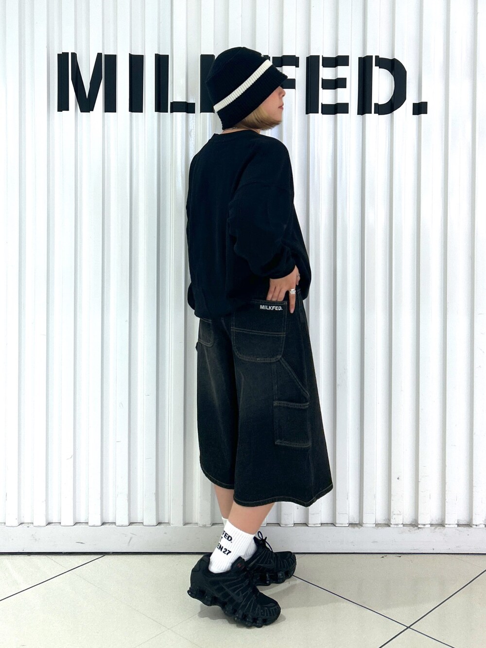 ブラック系のデニムパンツ、ブラック系のスウェット、ブラック系のハットを着用したレディースの秋コーディネートの2枚目の写真