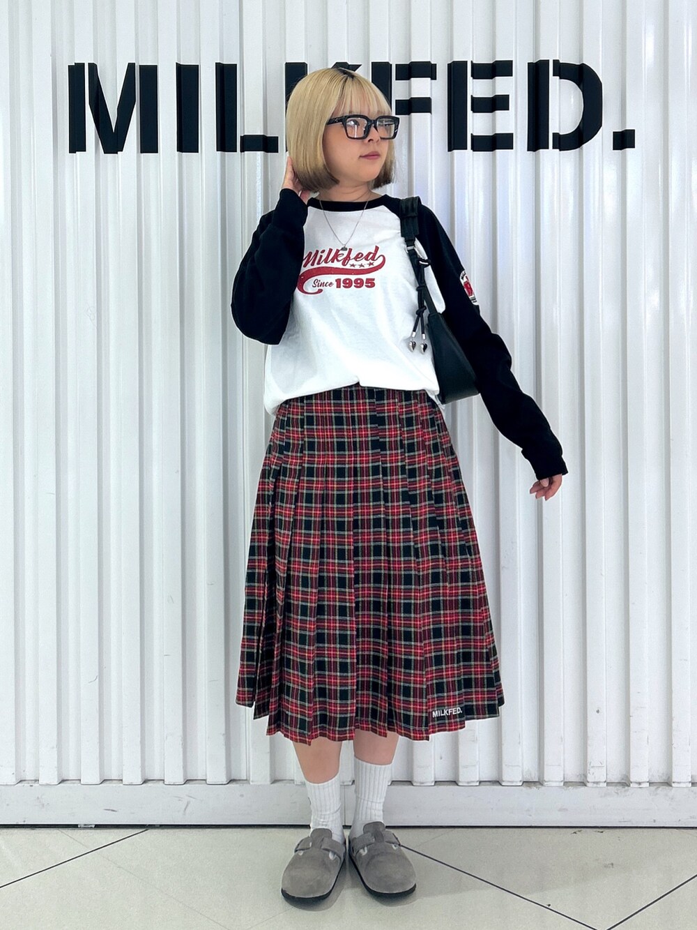 ブラック系のスカート、ホワイト系のTシャツ/カットソー、ブラック系のハンドバッグを着用したレディースの夏コーディネートの4枚目の写真