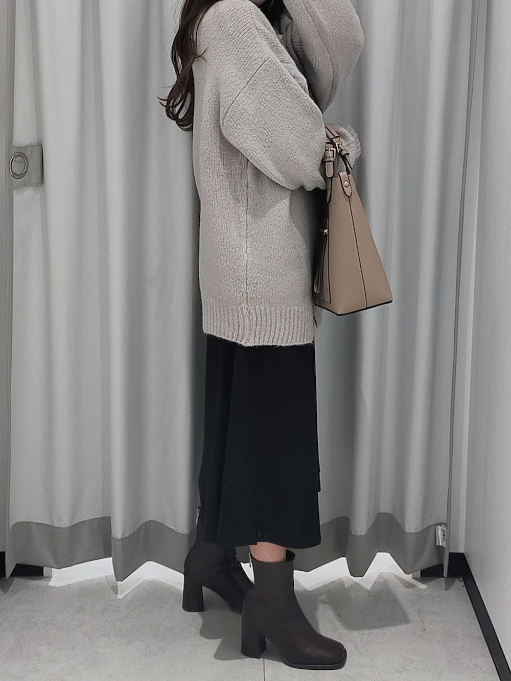ベージュ系のハンドバッグ、グレー系のカーディガン/ボレロ、ブラック系のワンピースを着用したレディースの秋コーディネートの2枚目の写真