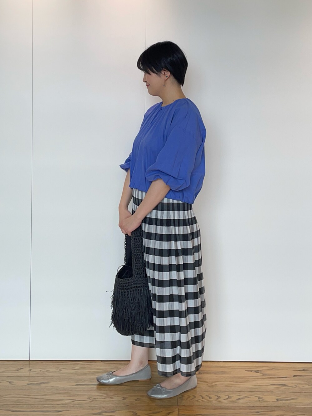 ブルー系のブルゾン、ブラック系のスカート、ブラック系のハンドバッグを着用したレディースの夏コーディネートの2枚目の写真