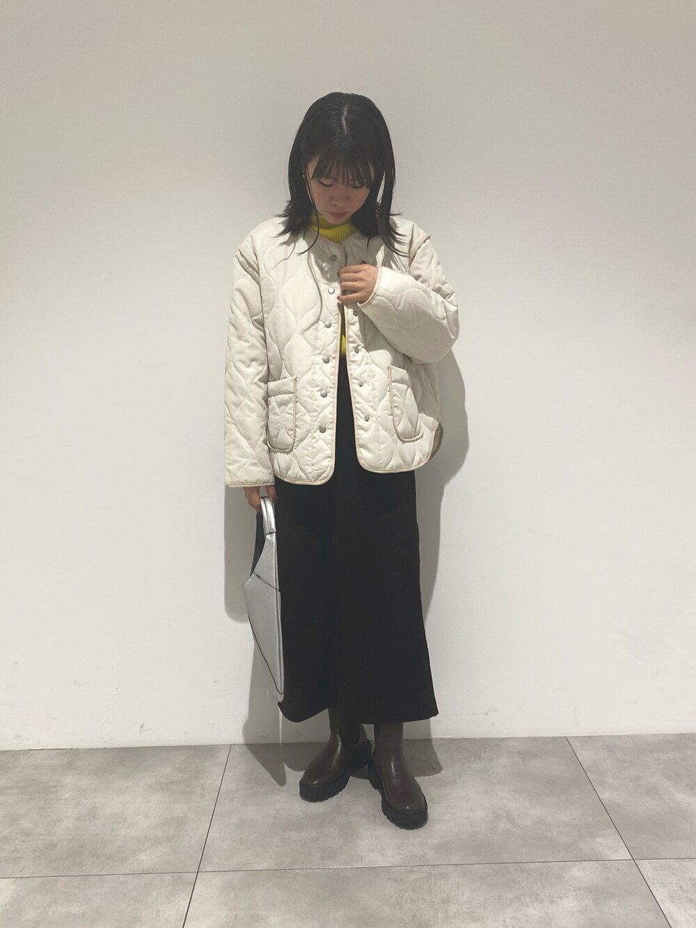 ホワイト系のジャケット/アウター、ブラウン系のブーツ、シルバー系のハンドバッグを着用したレディースの秋コーディネートの2枚目の写真