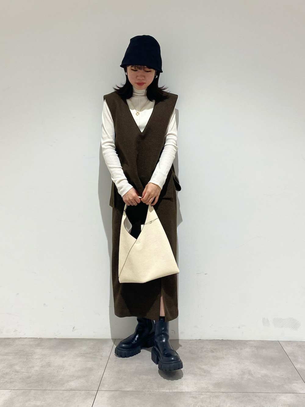 ブラック系のブーツ、ホワイト系のTシャツ/カットソー、ブラウン系のベストを着用したレディースの秋コーディネートの3枚目の写真