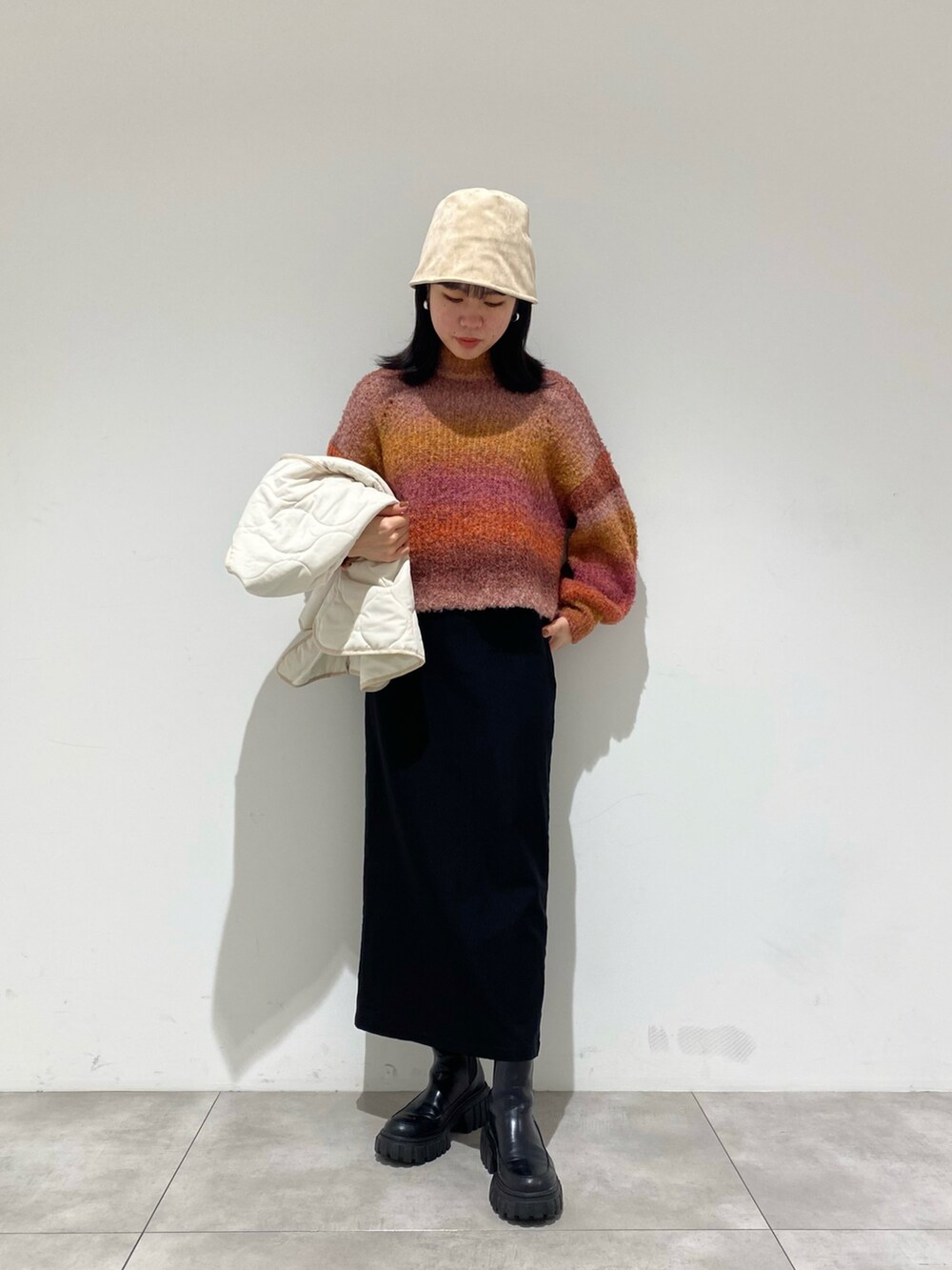 ホワイト系のダウンジャケット/コート、ピンク系のニット/セーター、ブラック系のスカートを着用したレディースの冬コーディネートの2枚目の写真