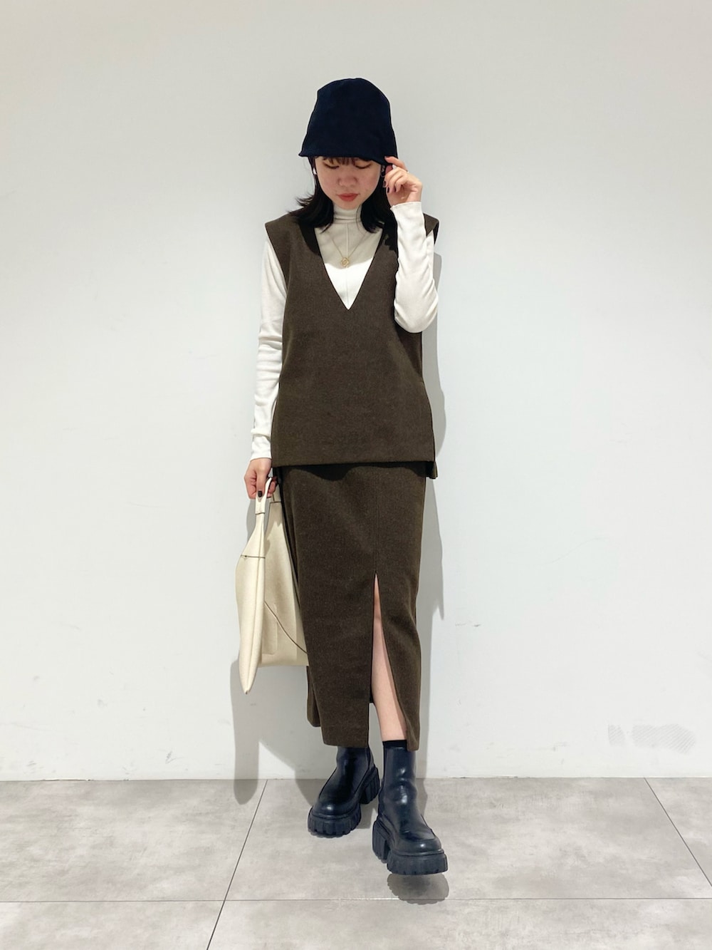 ブラック系のブーツ、ホワイト系のTシャツ/カットソー、ブラウン系のベストを着用したレディースの秋コーディネートの2枚目の写真