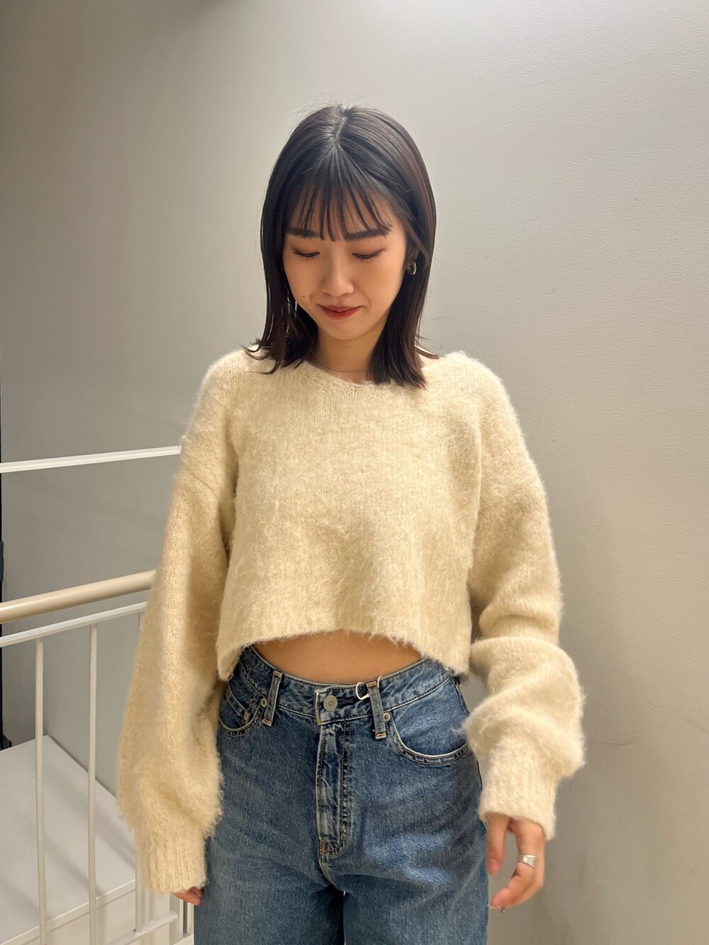 ホワイト系のニット/セーター、ブルー系のデニムパンツを着用したレディースの秋コーディネートの4枚目の写真