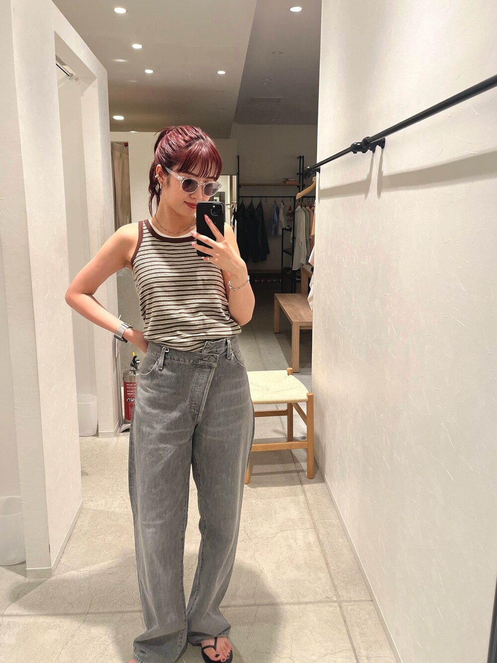 ブラウン系のタンクトップ、ブラック系のデニムパンツ、ブラック系のサンダルを着用したレディースの夏コーディネートの3枚目の写真