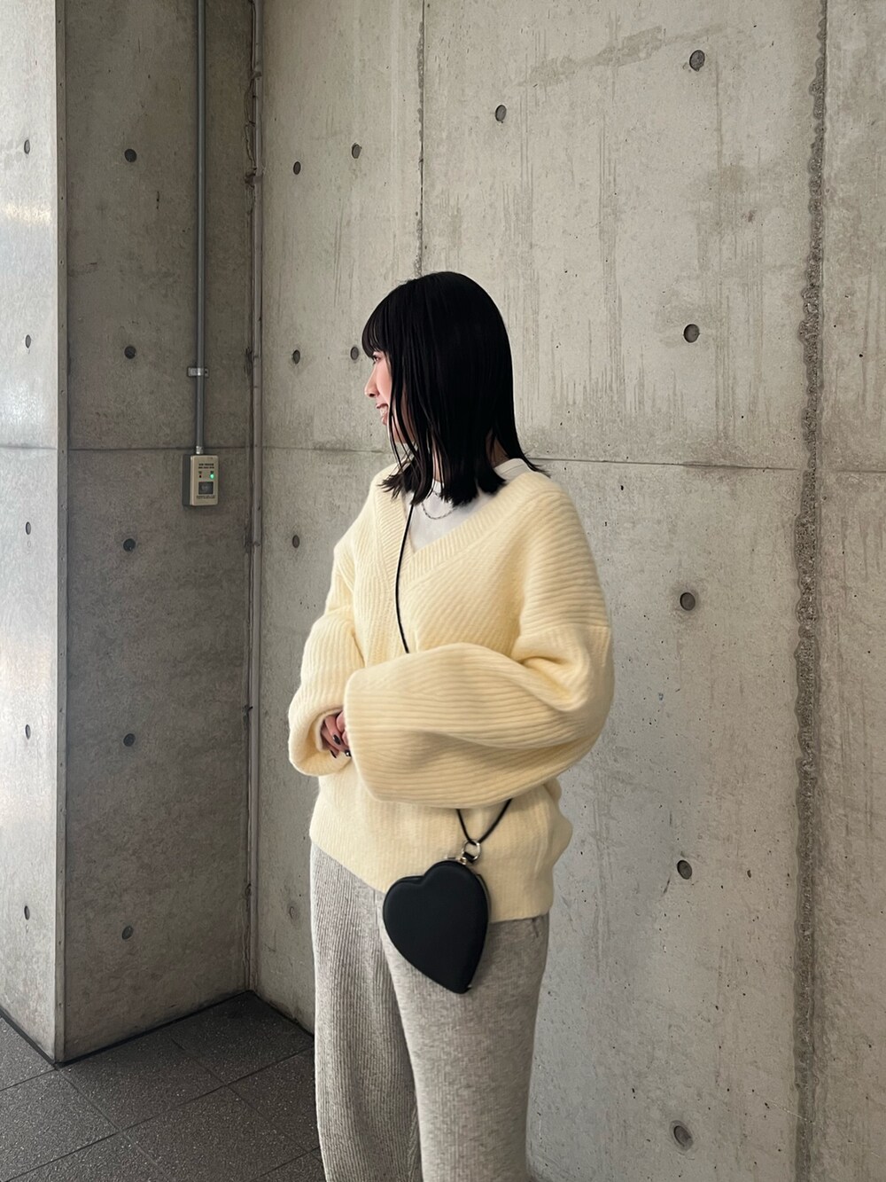 ホワイト系のニット/セーター、グレー系のその他パンツ、ブラック系のショルダーバッグを着用したレディースの秋コーディネートの4枚目の写真