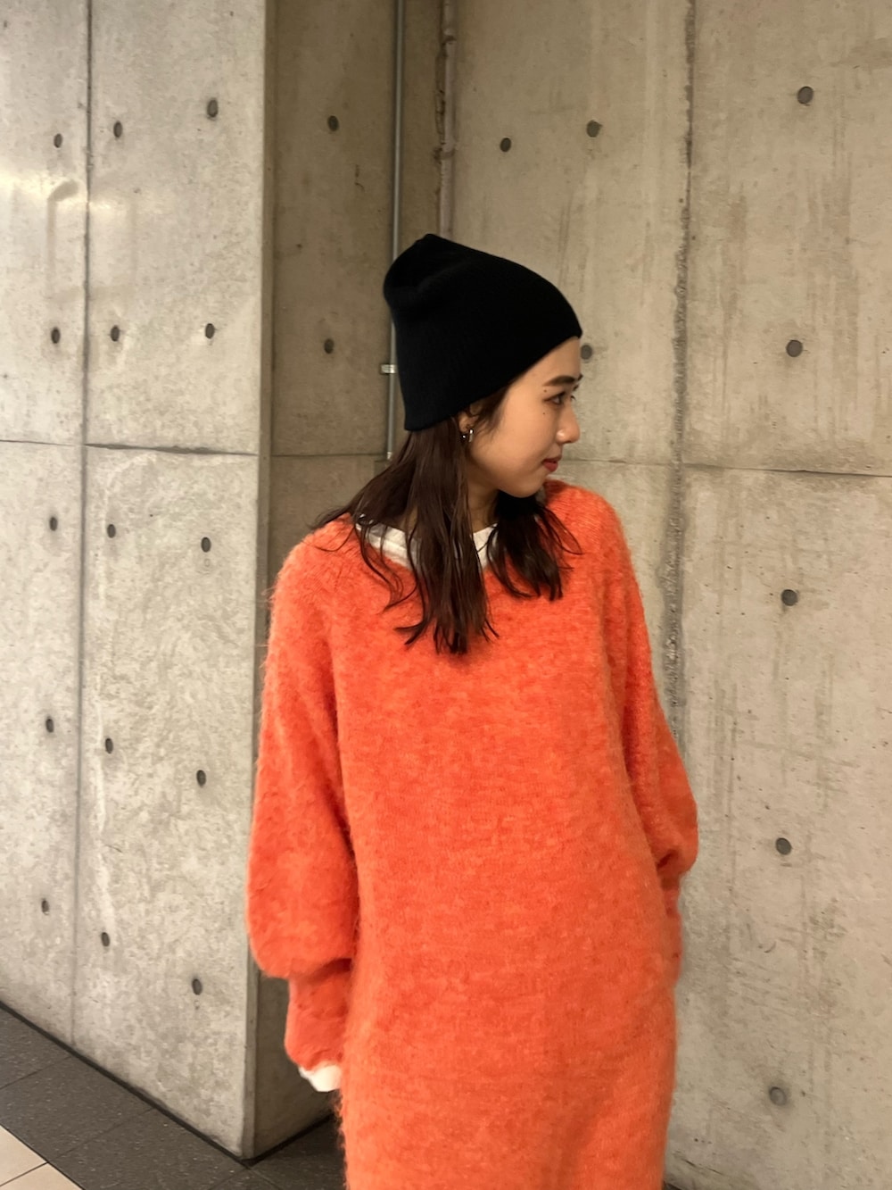 オレンジ系のワンピース、ブラック系のニットキャップ/ビーニーを着用したレディースの冬コーディネートの5枚目の写真