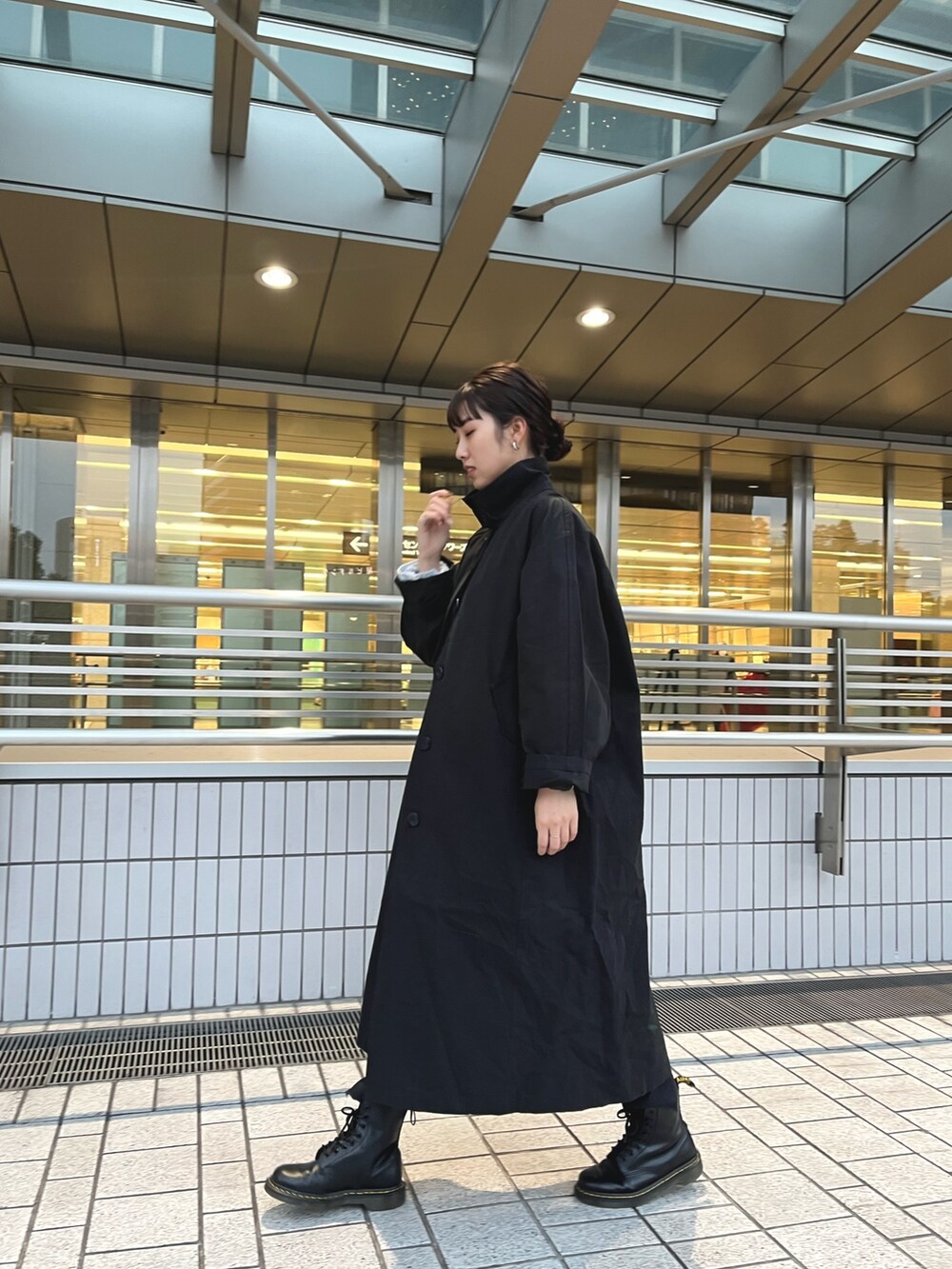 ブラック系のステンカラーコート、ブルー系のニット/セーター、ブラック系のデニムパンツを着用したレディースの冬コーディネートの3枚目の写真