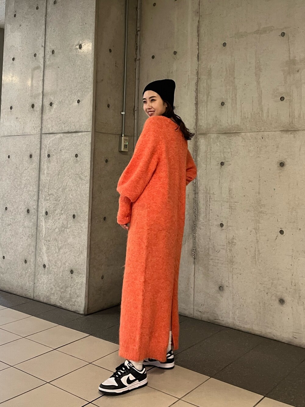 オレンジ系のワンピース、ブラック系のニットキャップ/ビーニーを着用したレディースの冬コーディネートの3枚目の写真