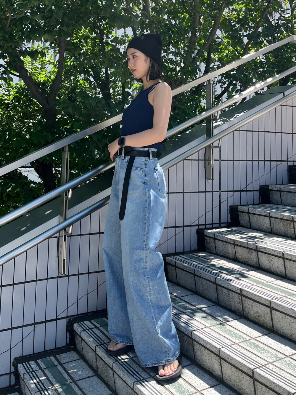 ブルー系のタンクトップ、ブルー系のデニムパンツ、ブラック系のベルトを着用したレディースの夏コーディネートの4枚目の写真