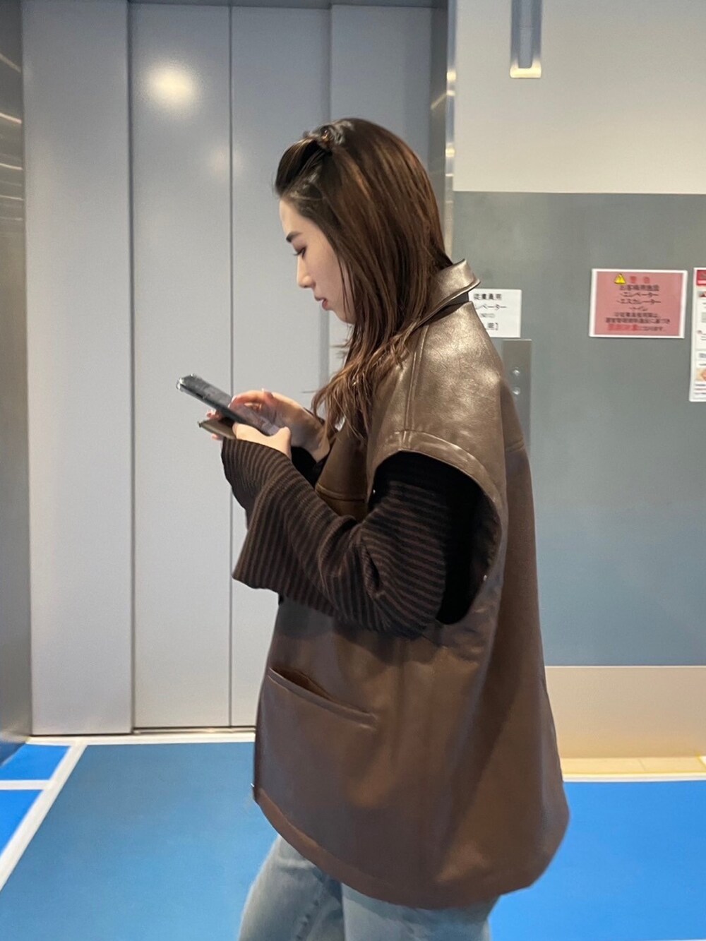 ブラウン系のブルゾン、ブラウン系のニット/セーター、ブルー系のデニムパンツを着用したレディースの冬コーディネートの4枚目の写真