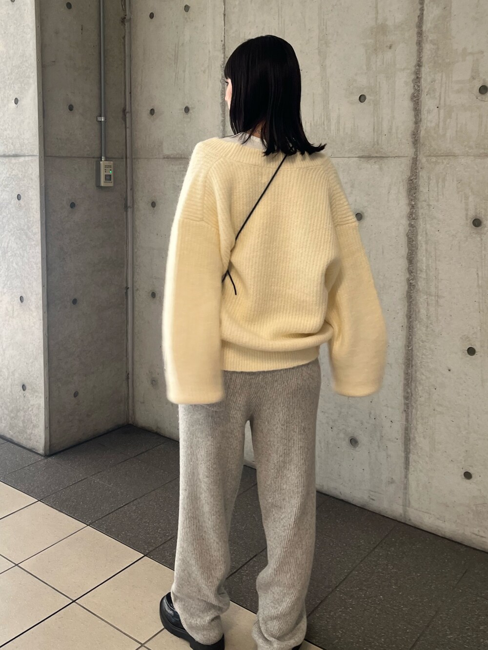 ホワイト系のニット/セーター、グレー系のその他パンツ、ブラック系のショルダーバッグを着用したレディースの秋コーディネートの3枚目の写真