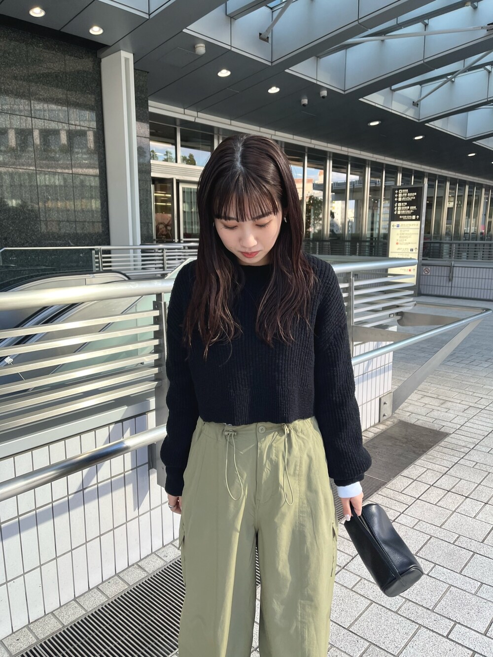 ブラック系のワンピース、グリーン系のカーゴパンツ、ブラック系のハンドバッグを着用したレディースの冬コーディネートの3枚目の写真