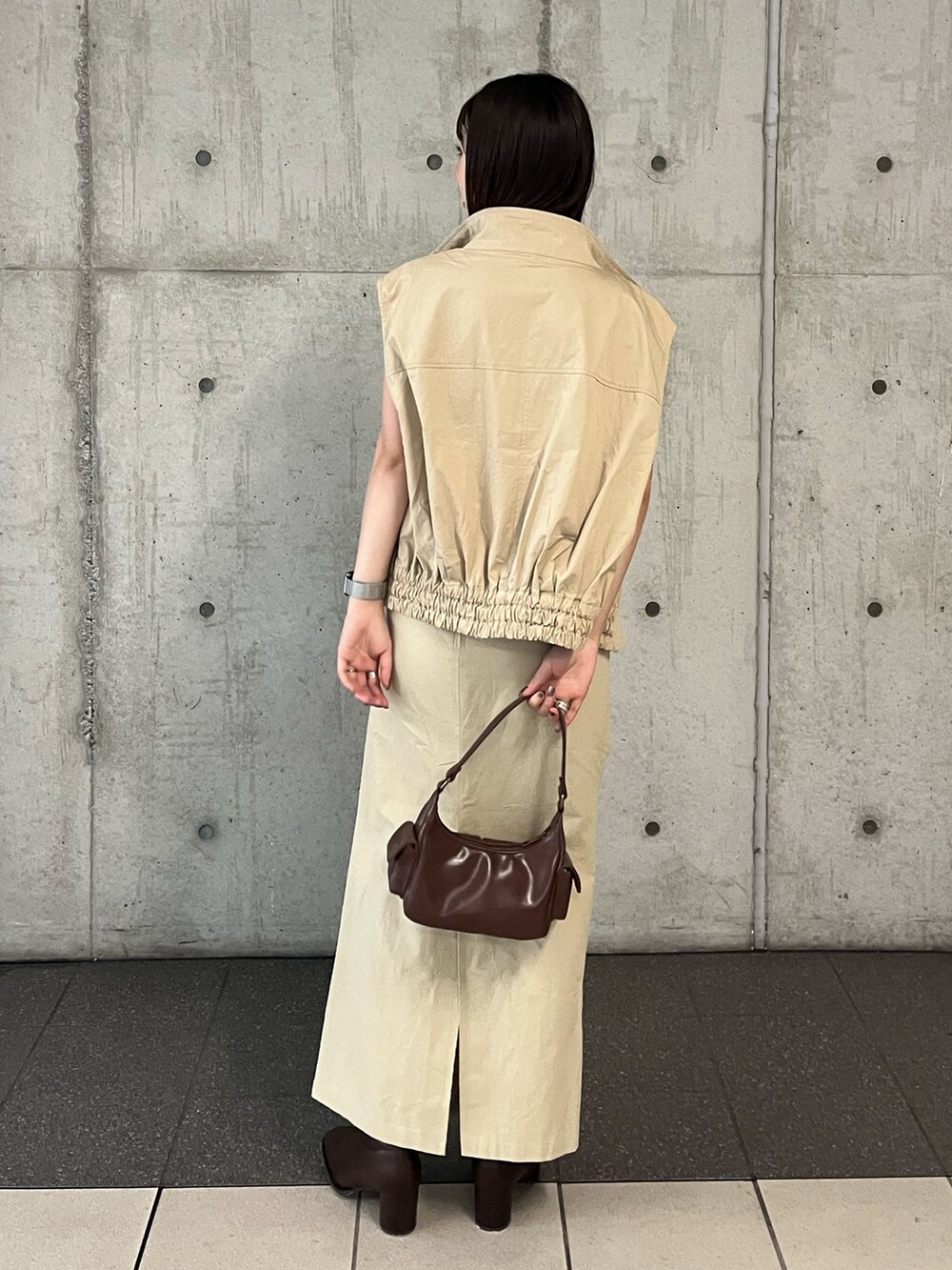 ベージュ系のベスト、ベージュ系のスカート、ブラウン系のハンドバッグを着用したレディースの夏コーディネートの4枚目の写真