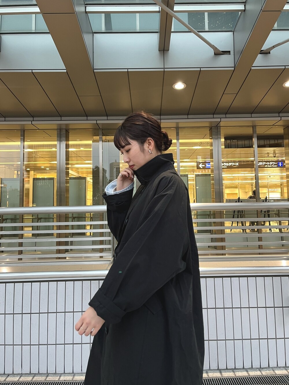 ブラック系のステンカラーコート、ブルー系のニット/セーター、ブラック系のデニムパンツを着用したレディースの冬コーディネートの4枚目の写真