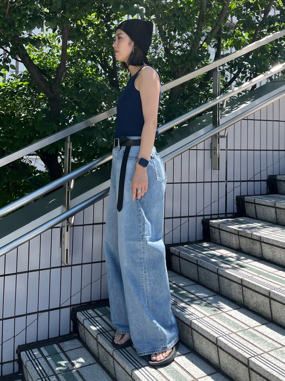 ブルー系のタンクトップ、ブルー系のデニムパンツ、ブラック系のベルトを着用したレディースの夏コーディネートの3枚目の写真