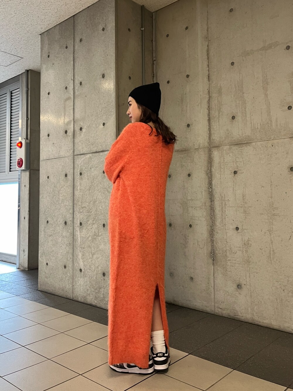 オレンジ系のワンピース、ブラック系のニットキャップ/ビーニーを着用したレディースの冬コーディネートの4枚目の写真
