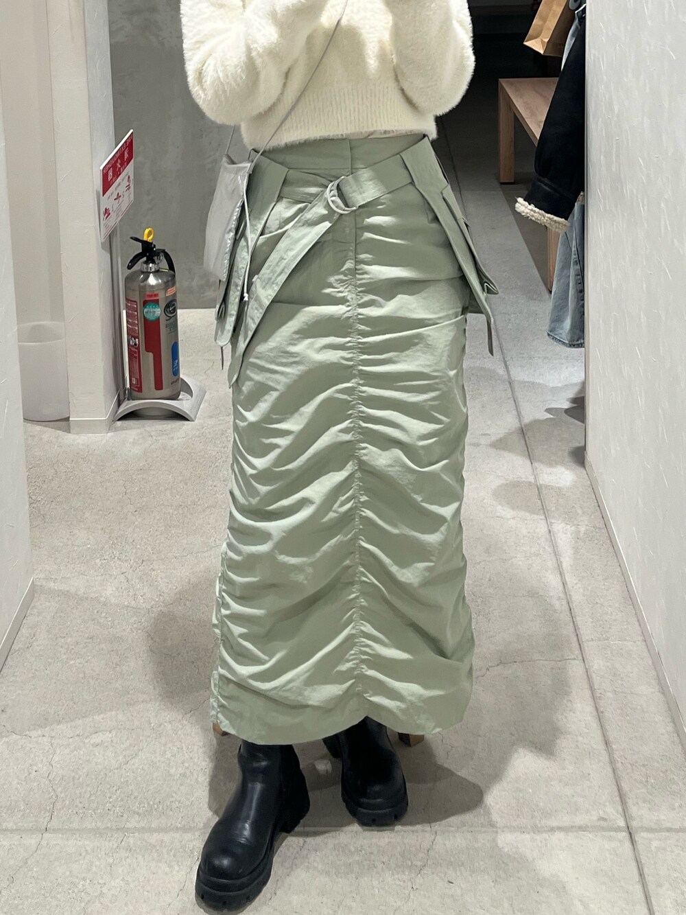 シルバー系のショルダーバッグ、グリーン系のスカートを着用したレディースの冬コーディネートの4枚目の写真