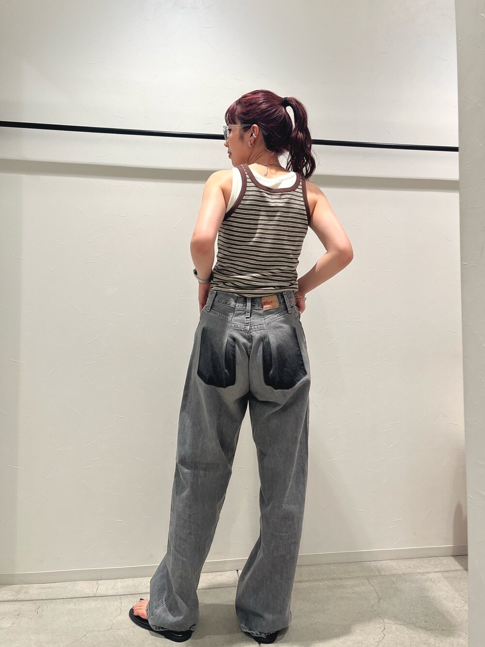 ブラウン系のタンクトップ、ブラック系のデニムパンツ、ブラック系のサンダルを着用したレディースの夏コーディネートの2枚目の写真