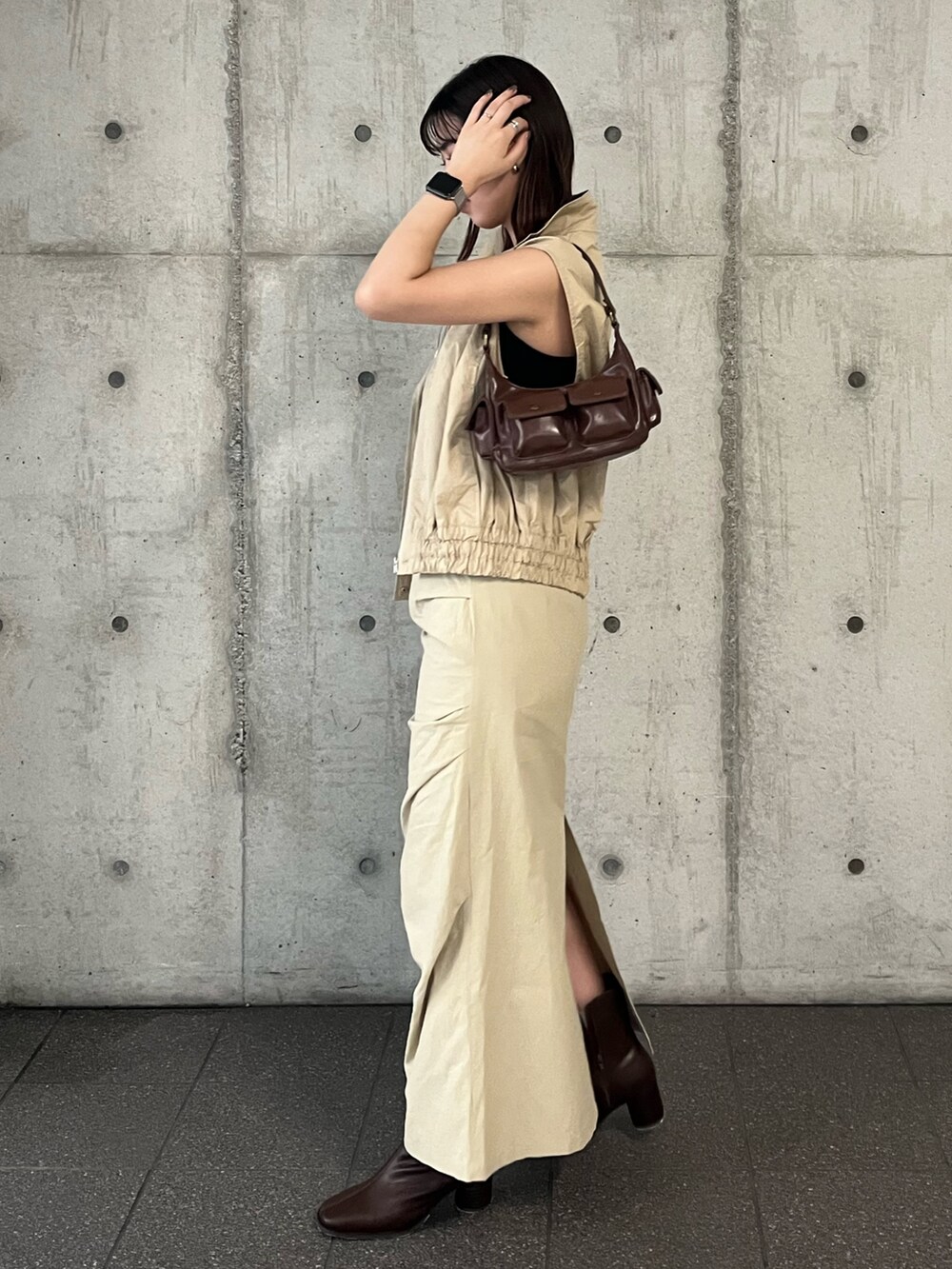 ベージュ系のベスト、ベージュ系のスカート、ブラウン系のハンドバッグを着用したレディースの夏コーディネートの3枚目の写真