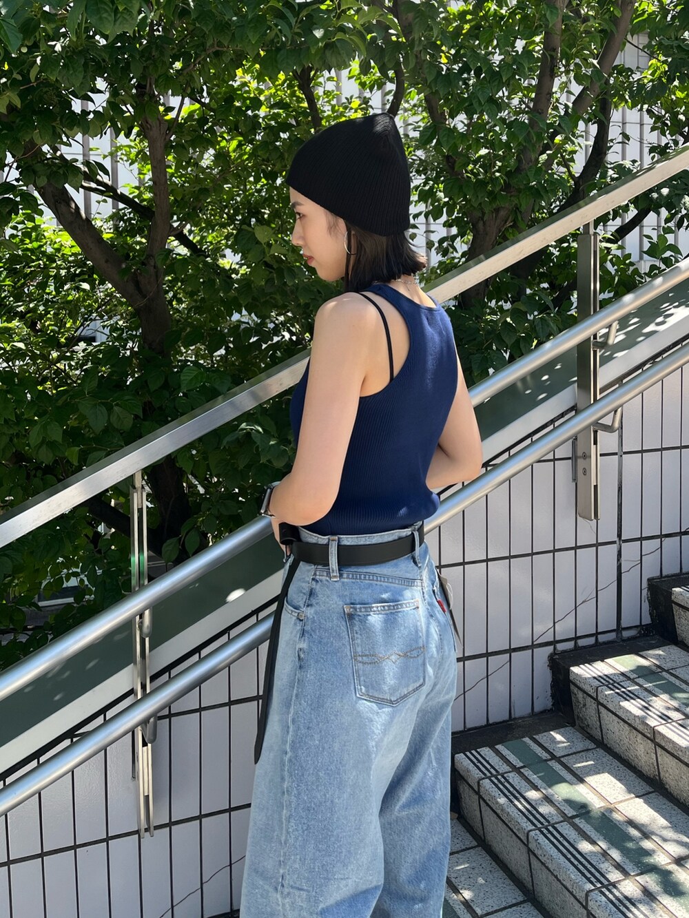 ブルー系のタンクトップ、ブルー系のデニムパンツ、ブラック系のベルトを着用したレディースの夏コーディネートの5枚目の写真