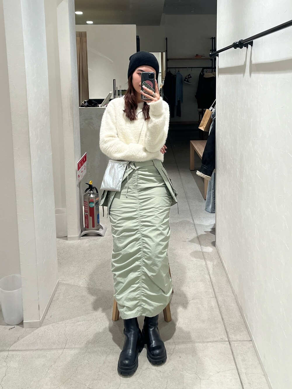 シルバー系のショルダーバッグ、グリーン系のスカートを着用したレディースの冬コーディネートの2枚目の写真
