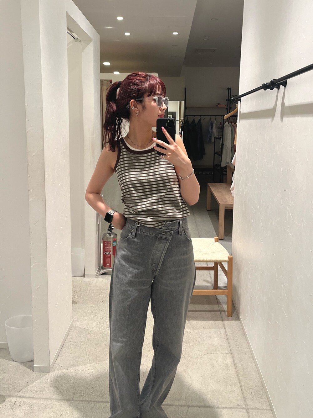 ブラウン系のタンクトップ、ブラック系のデニムパンツ、ブラック系のサンダルを着用したレディースの夏コーディネートの4枚目の写真