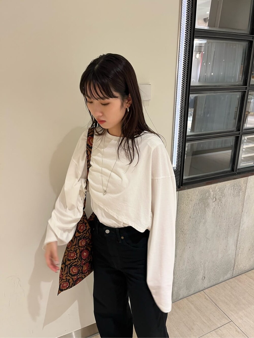 ホワイト系のTシャツ/カットソー、ブラック系のデニムパンツ、ブラック系のパンプスを着用したレディースの秋コーディネートの3枚目の写真