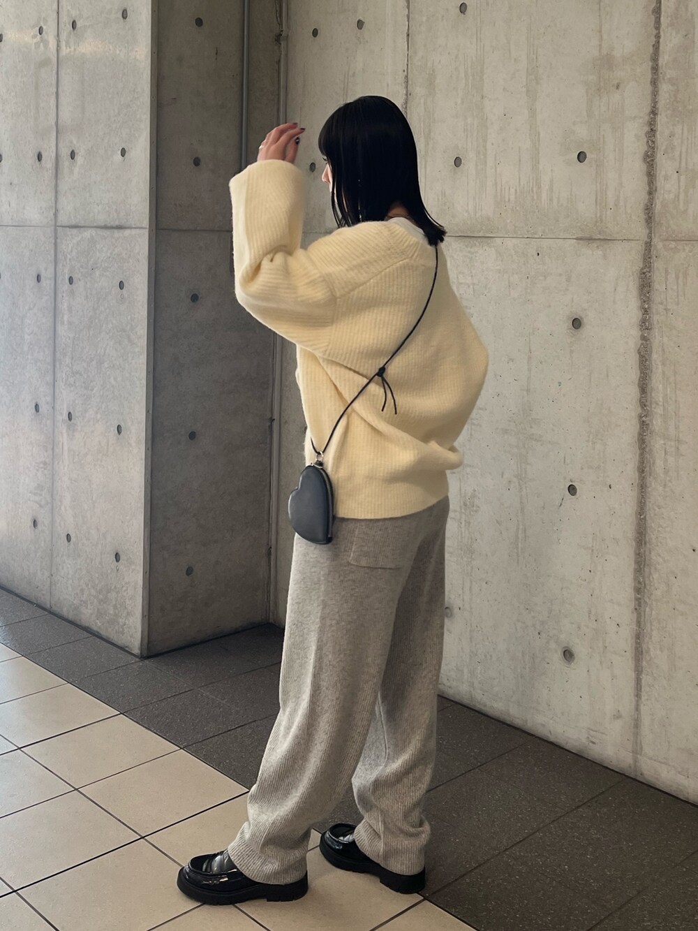 ホワイト系のニット/セーター、グレー系のその他パンツ、ブラック系のショルダーバッグを着用したレディースの秋コーディネートの2枚目の写真