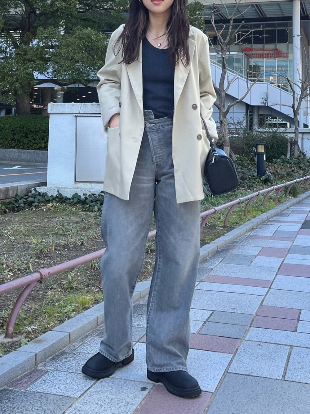 ベージュ系のテーラードジャケット、グレー系のタンクトップ、ブラック系のデニムパンツを着用したレディースの冬コーディネートの2枚目の写真